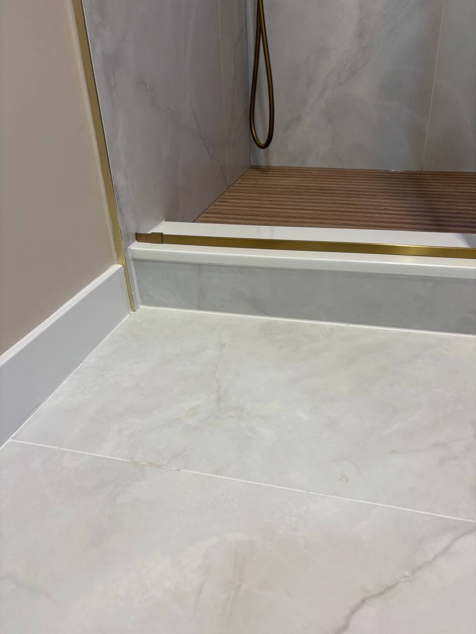 Marble floor tiles with gold brass trim at shower entry