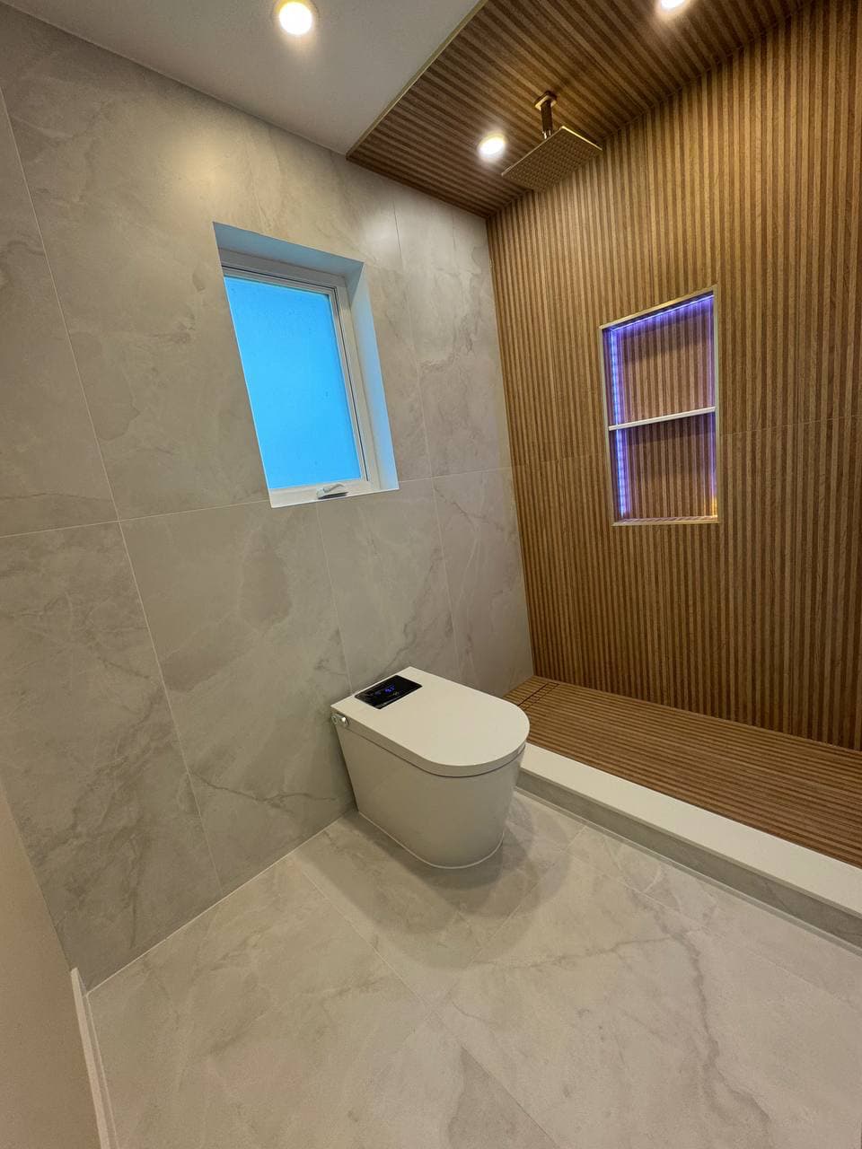 Smart toilet with marble walls, wood slat accent wall, and LED-lit niche