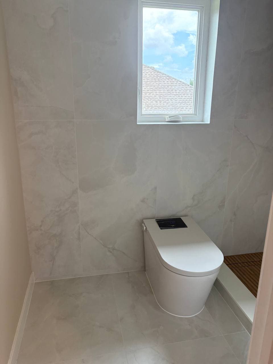 Smart toilet area with marble walls and window with natural light
