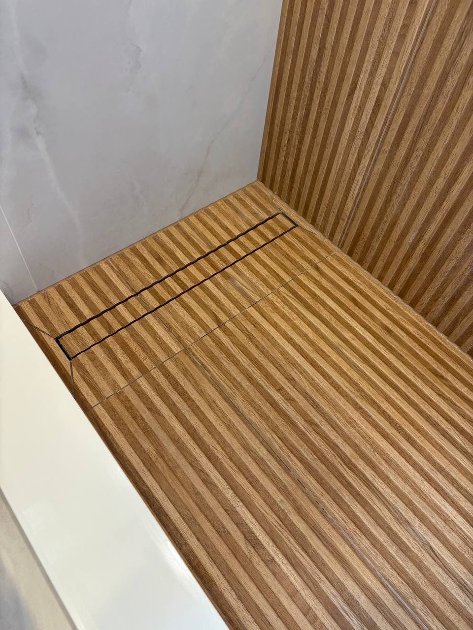 Overhead view of teak slatted shower floor with integrated linear drain