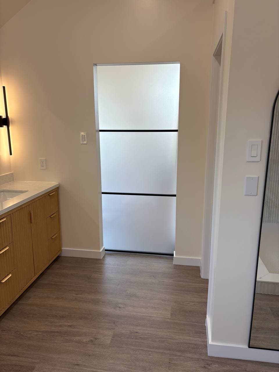 Fluted wood vanity with quartz countertop and frosted glass panel door